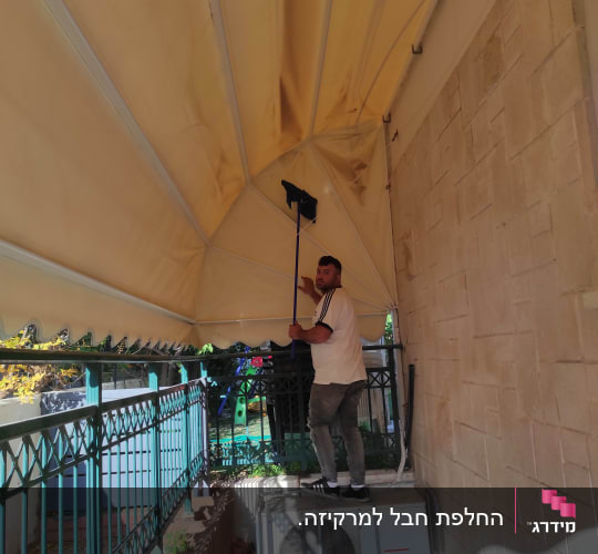 אדם מנקה סוכך בעזרת מטאטא ארוך